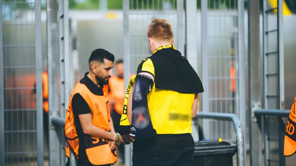 A steward carrying out a bag search at a stadium entrance gate